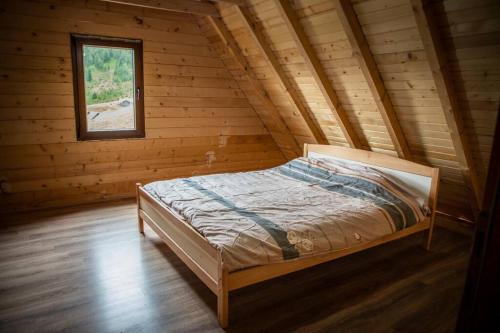 a bed in a log cabin with a window at Mariash Woodhouse - Beleg Mountains in Deçan