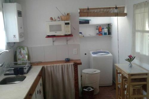 uma pequena cozinha com um lavatório e um micro-ondas em Casa Lola em Barra de Valizas
