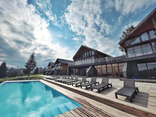 a resort with a swimming pool with benches and a building at SevenHills chalet in Yablunytsya