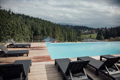 a swimming pool on a wooden deck with chairs at SevenHills chalet in Yablunytsya