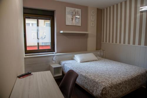 Habitación con cama, mesa y ventana en Hostal Gud Salamanca, en Salamanca