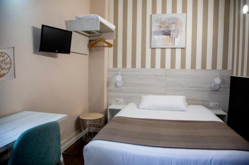 サラマンカにあるHostal Gud Salamancaのベッドとテレビ付きのホテルルーム