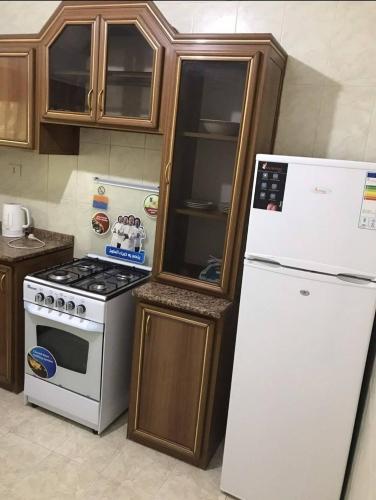 a kitchen with a white refrigerator and a stove at شقة مفروشة قريبة من البوابة الشمالية للجامعة الاردنية in Amman