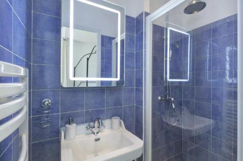 ein blau gefliestes Bad mit einem Waschbecken und einem Spiegel in der Unterkunft La Terrasse de Mademoiselle in Versailles