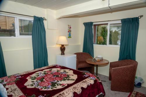a bedroom with a bed and a table and two windows at Guest Suite Private Retreat- Honeymoon Suite- J-1 in Abbotsford