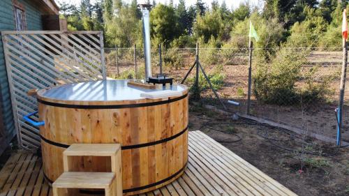 a hot tub sitting on a wooden deck with two stools at Cabañas Vista Hermosa Radal 7 Tazas in El Torreón