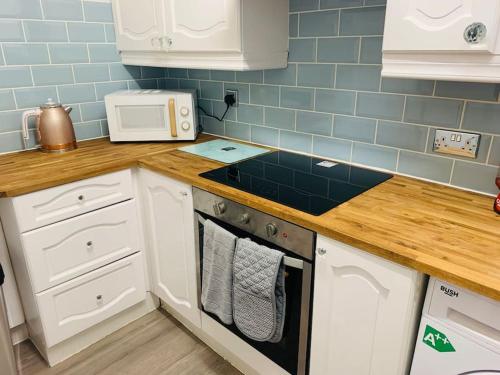 una cucina con armadi bianchi e piastrelle blu di Aylesbury Apartment for Contractors and Holidays ad Aylesbury