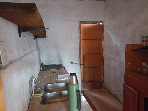 una pequeña cocina con un extintor verde en una habitación en Casa CAMALDALU en Unquillo