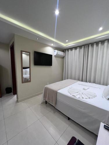 a bedroom with a bed and a television on the wall at Pousada Arraial Tropical in Arraial do Cabo