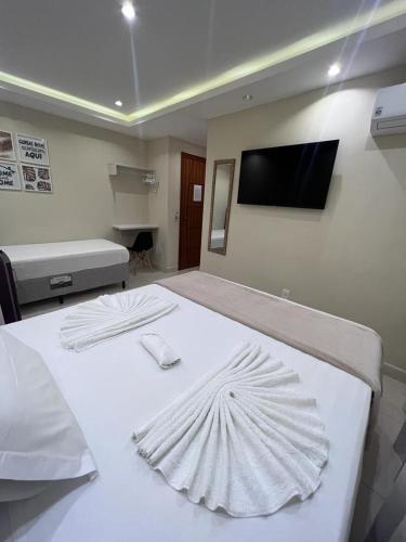 a bedroom with a white bed with a flat screen tv at Pousada Arraial Tropical in Arraial do Cabo