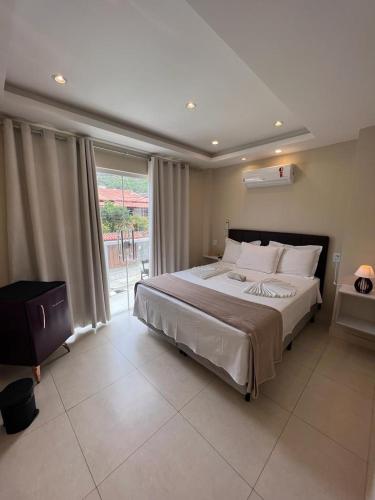 a bedroom with a large bed and a large window at Pousada Arraial Tropical in Arraial do Cabo