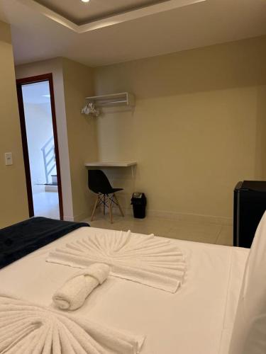 a white bed with a towel on top of it at Pousada Arraial Tropical in Arraial do Cabo