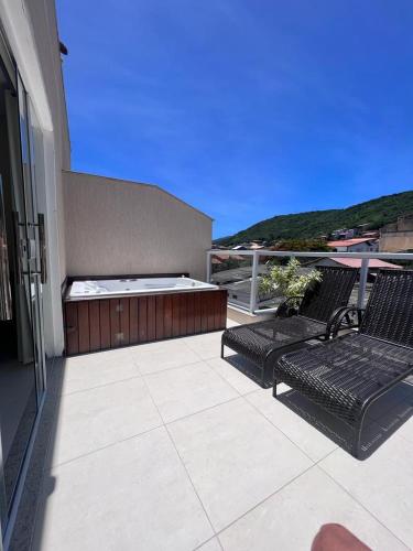a patio with two chairs and a bed on a building at Pousada Arraial Tropical in Arraial do Cabo