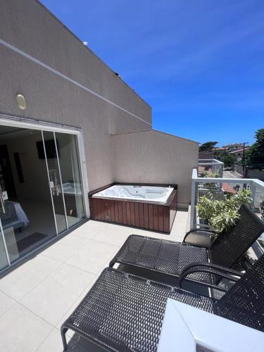 a patio with two chairs and a hot tub on a building at Pousada Arraial Tropical in Arraial do Cabo