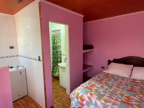 a bedroom with purple walls and a bed and a bathroom at Hospedaje Los Abuelos in Pichilemu