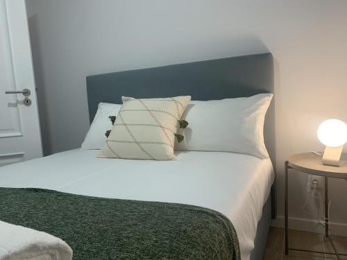 a bed with white pillows and a green blanket at Torreira Vacation Homes - Ria House in Torreira