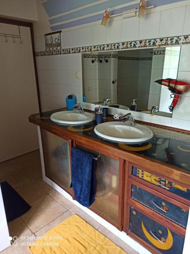 a bathroom with two sinks and a mirror at La Maison Du Voyage in Tevaitoa