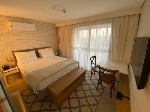 a bedroom with a bed and a desk and a window at Carpe Diem Spa & boutique in Campos do Jordão