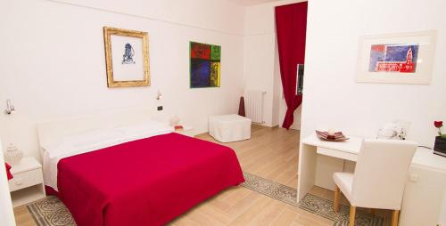 a white bedroom with a red bed and a desk at La Dimora dell' Architetto in Gravina in Puglia