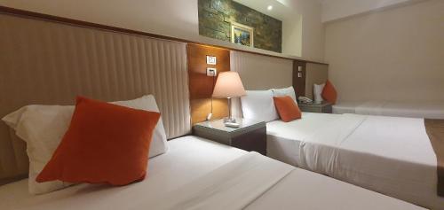 Habitación de hotel con 2 camas con almohadas de color naranja en River Nile Edge Boutique Hotel & Restaurant, en El Cairo