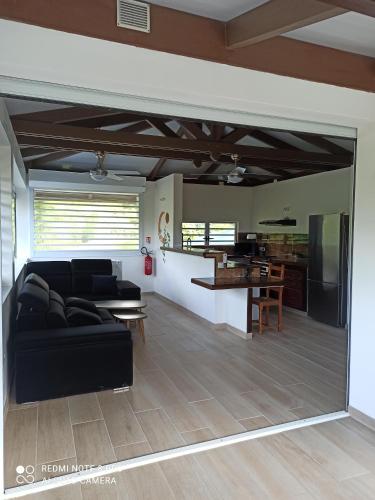 a living room with a black couch and a kitchen at La Maison Du Voyage in Tevaitoa
