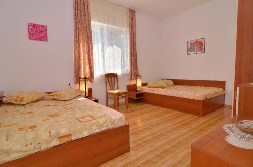 a bedroom with two beds and a chair and a window at Royal Villas in Bryastovets