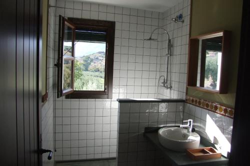 een wit betegelde badkamer met een wastafel en 2 ramen bij Casa Olea hotel rural in Priego de Córdoba