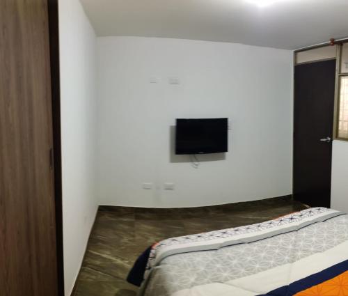 1 dormitorio con 1 cama y TV en la pared en Que chimba de apto., en Bogotá