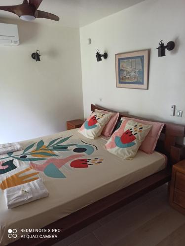 a bedroom with a bed with colorful pillows at La Maison Du Voyage in Tevaitoa