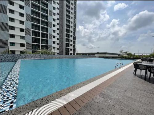 uma piscina com uma mesa e alguns edifícios em Desaru Dhancell Executive Homestay All Bedrooms With NETFLIX em Desaru