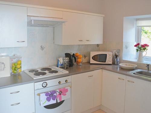 a kitchen with white cabinets and a stove top oven at Chestnut - 28866 in Stokeinteignhead