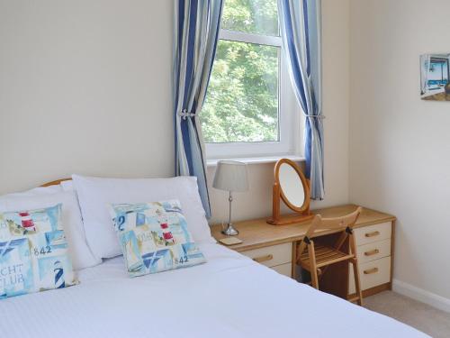 een slaapkamer met een bed met blauwe gordijnen en een raam bij Chestnut - 28866 in Stokeinteignhead