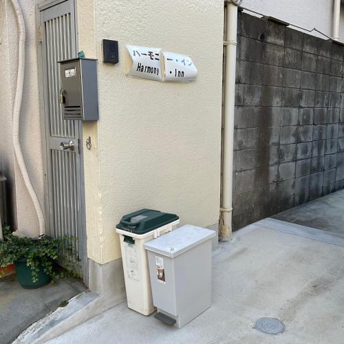 un par de cubos de basura sentados fuera de un edificio en ハーモニーイン, en Osaka