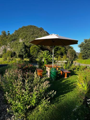 a picnic table with an umbrella in a garden at Wisteria Way in Opononi