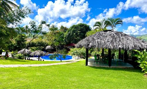 a resort with a grass umbrella and a swimming pool at Hotel Rincon Rubi in Las Galeras