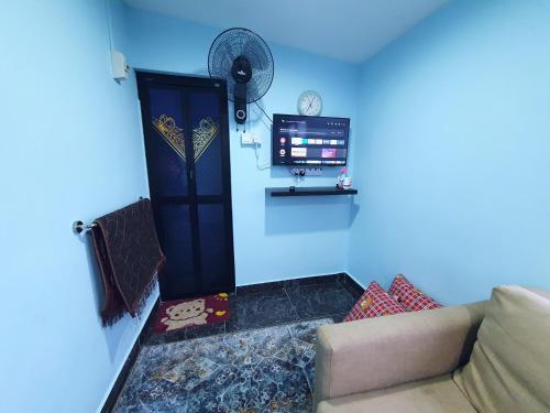 een woonkamer met een bank en een blauwe muur bij Cabin stay with Sunrise and plane spotting view in Shah Alam
