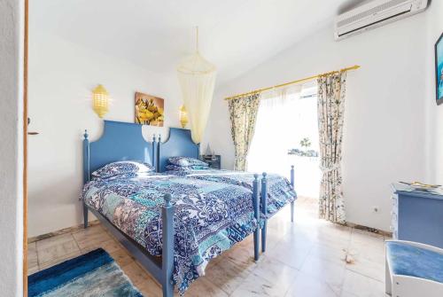 カルヴォエイロにあるCasa Fatinhaのベッドルーム(青いベッド1台、窓付)