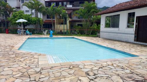 a swimming pool with a stone floor and a house at Duplex Top! - Visit and Love Us - Piccola Marina Bracuhy in Angra dos Reis
