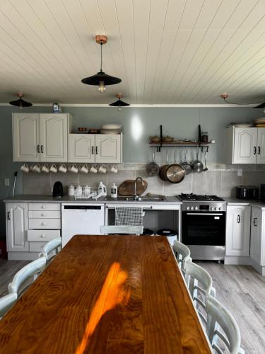 a kitchen with a wooden table and white cabinets at Wisteria Way in Opononi