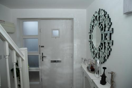 un couloir blanc avec une porte et un miroir dans l'établissement Broughton Haven 5 Beds House Free WiFi, Free parking, NETFLIX, à Milton Keynes