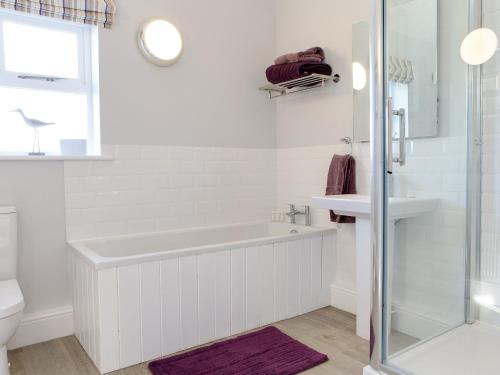 ein weißes Badezimmer mit einer Badewanne und einem Waschbecken in der Unterkunft Lodge Cottage in Scalby