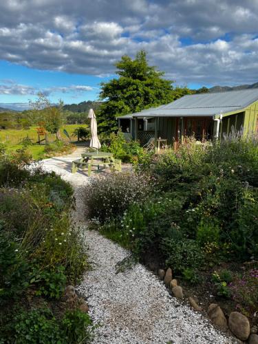 a garden with a building and a table and chairs at Wisteria Way in Opononi