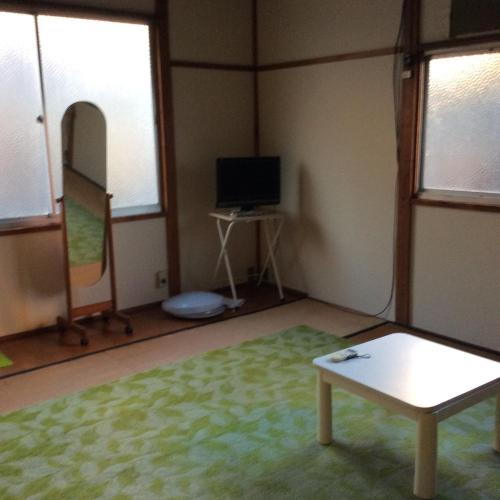 a room with a room with a table and a tv at ハーモニーイン in Osaka