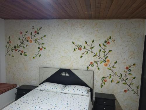 a bedroom with a bed with flowers on the wall at Hotel Bethesda in Aguachica