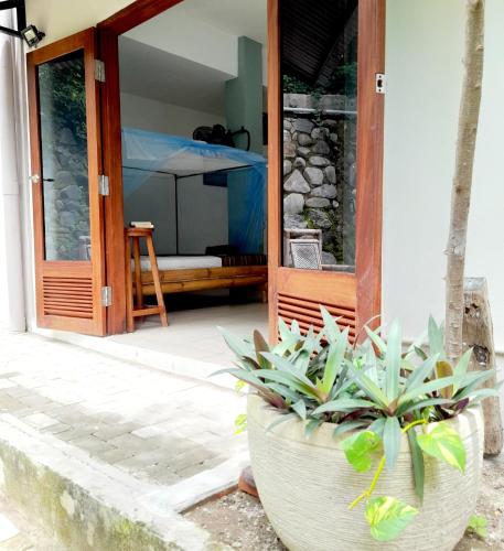 a porch with two large pots of plants in front of a door at Merdeka House in Maluk
