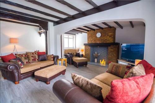 a living room with couches and a tv and a fireplace at A Bright and Spacious Gem in Staines