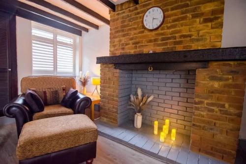 a living room with a brick fireplace with a clock at A Bright and Spacious Gem-Newly renovated house in Staines