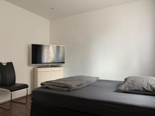 1 dormitorio con 1 cama, 1 silla y TV de pantalla plana en AT-Apartments - Hannover-Mitte, en Hannover