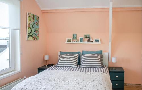 Schlafzimmer mit rosa Wänden und einem Bett mit gestreiften Kissen in der Unterkunft 3 Bedroom Nice Home In Groede in Groede