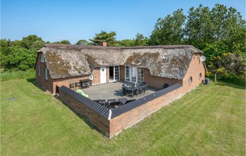 an old brick house with a thatched roof on a field at Lovely Home In Ringkøbing With Sauna in Ringkøbing